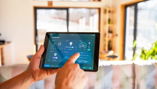 Unrecognisable man using tablet with smart home control functions at home.